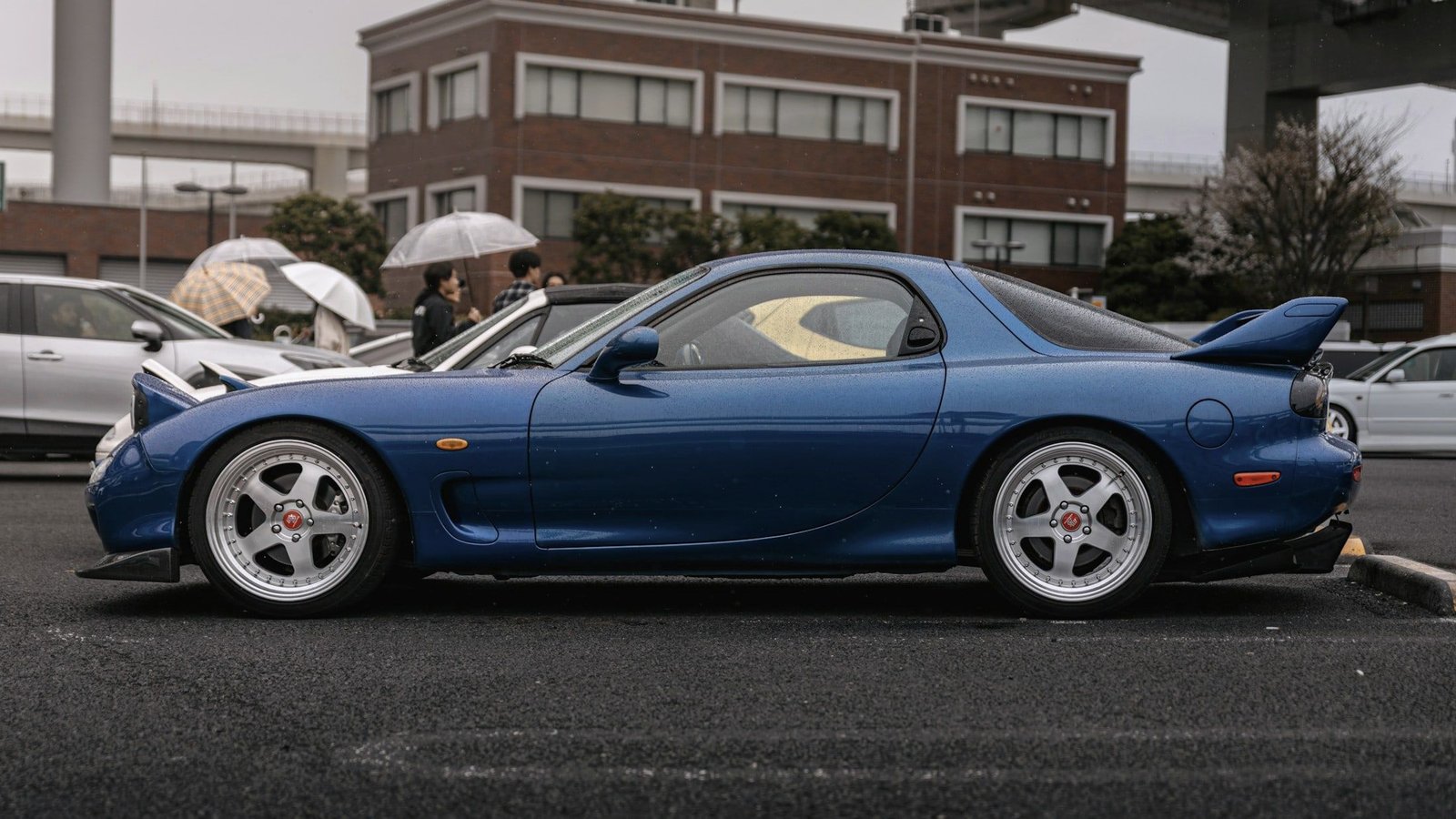 Blue Mazda RX-7 side profile on wet tarmac