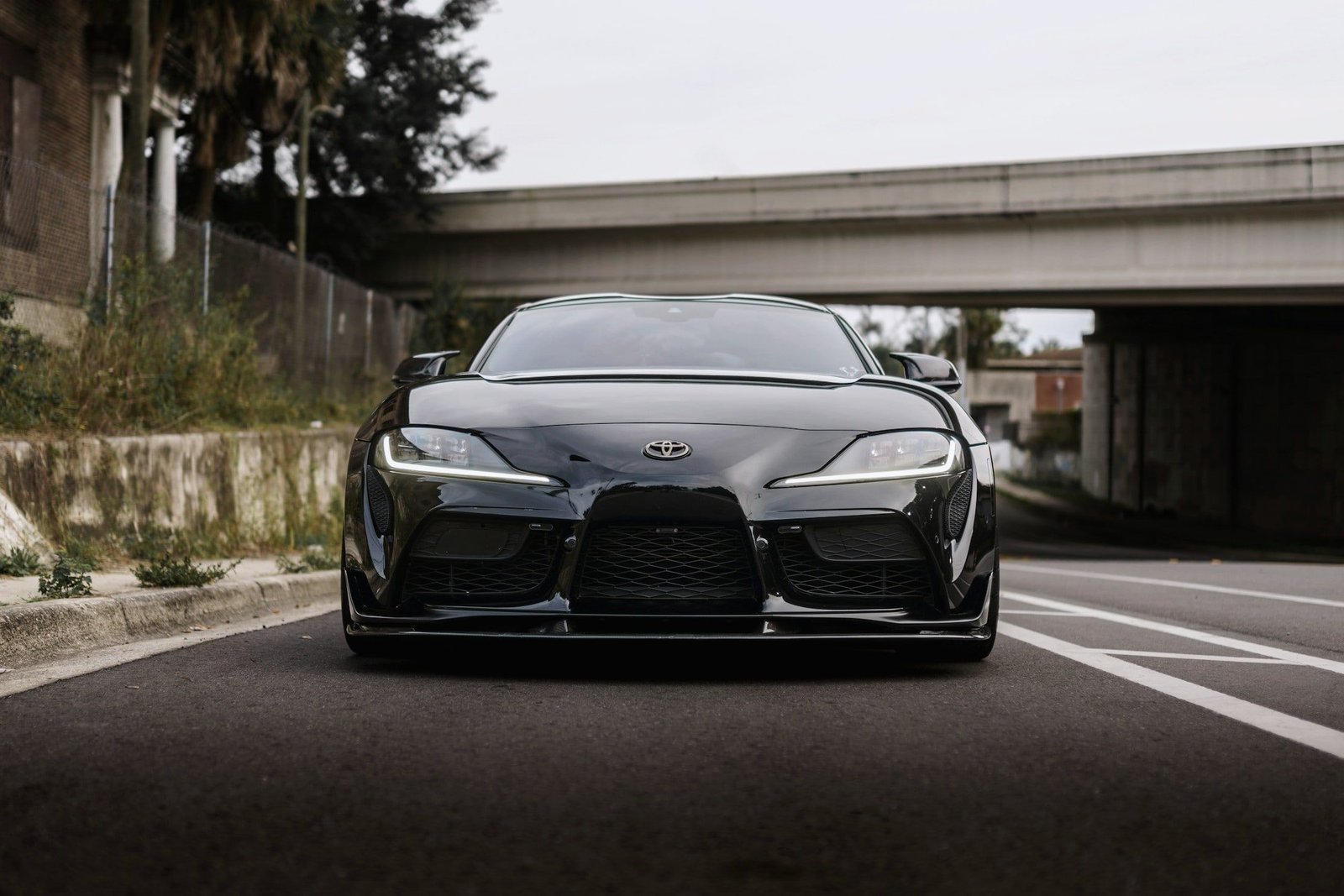 Black Toyota GR Supra under a flyover