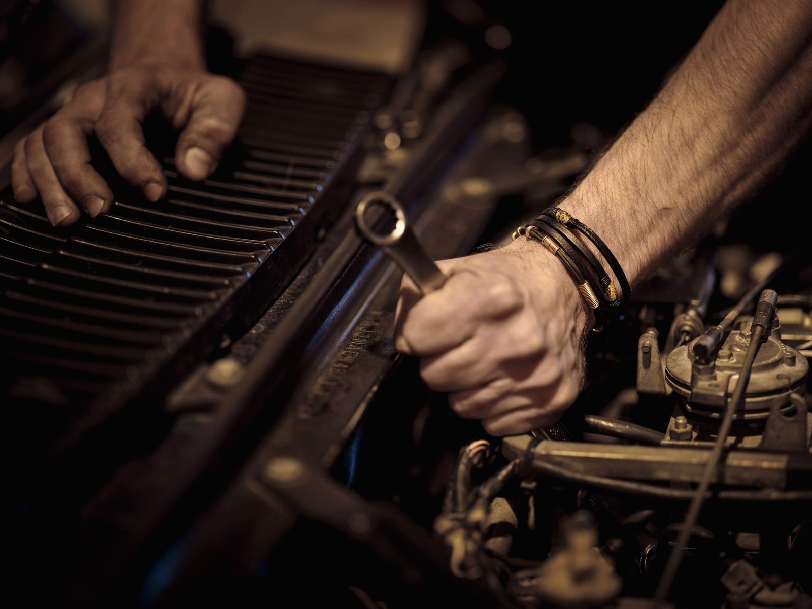 Hands turning a wrench in an engine bay
