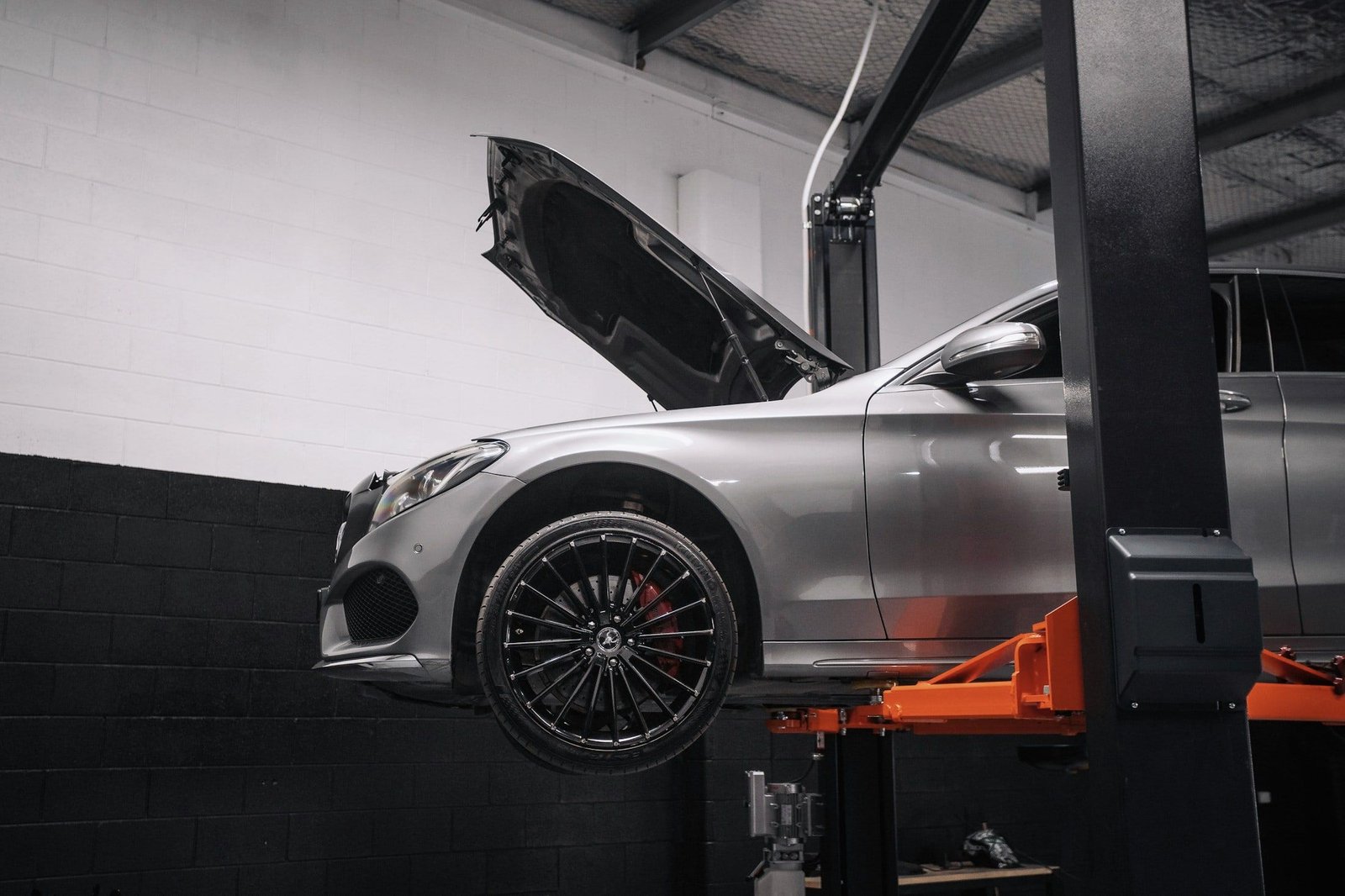 Silver car raised on a two-post lift in a clean workshop